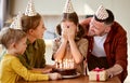 Cute little girl making wish while celebrating Birthday with family at home