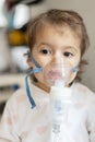 Cute little girl in the mask of an inhaler. Procedure of inhalation at home. Kid taking respiratory therapy with nebulizer Royalty Free Stock Photo