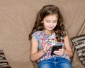 Cute little girl with mobile phone sitting on the sofa Royalty Free Stock Photo