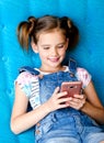 Cute little girl with mobile phone sitting on the sofa Royalty Free Stock Photo