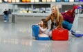 Cute little girl and mother at the airport. Tired family sitting on ground and waiting for delayed flight. Woman and child by Royalty Free Stock Photo