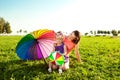 Cute little girl with mother colored balloons and rainbow umbrella holding in the park. Smiling child and mom on a field with fl Royalty Free Stock Photo