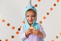 Cute little girl in narwhal costume holding cookie at home. Halloween party