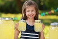 Cute little girl with natural lemonade in park. Summer refreshing