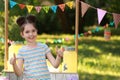 Cute little girl near lemonade stand in park. Summer refreshing natural drink