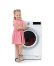 Cute little girl near washing machine with laundry Royalty Free Stock Photo