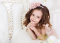 Portrait of a cute little girl in a bright studio with a crown on her head looking at the camer . Happy childhood concept. Close- Royalty Free Stock Photo