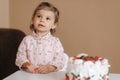 Cute little girl one and a hulf year old stand by delicious birthday cake. Eighteen month old girl verry happy and Royalty Free Stock Photo