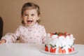 Cute little girl one and a hulf year old stand by delicious birthday cake. Eighteen month old girl verry happy and Royalty Free Stock Photo