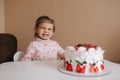 Cute little girl one and a hulf year old stand by delicious birthday cake. Eighteen month old girl verry happy and Royalty Free Stock Photo