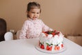 Cute little girl one and a hulf year old stand by delicious birthday cake. Eighteen month old girl verry happy and Royalty Free Stock Photo