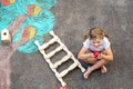 Cute little girl painting with colorful chalks apples harvest from apple tree on asphalt. Cute preschool child with Royalty Free Stock Photo