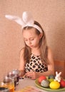Little girl painting easter eggs at home.
