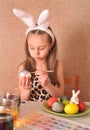 Little girl painting easter eggs at home.