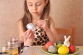 Little girl painting easter eggs at home.