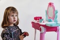 Cute little girl painting her nails. Pretty Little Girl Playing With Cosmetics Near Dressing Table In The Room Royalty Free Stock Photo