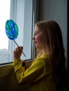 Cute little girl painting planet on window at home. Happy Earth Day April 22 greeting message.Creative family leisure