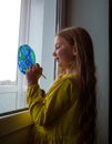 Cute little girl painting planet on window at home 4K. Happy Earth Day April 22 greeting message.Creative family leisure