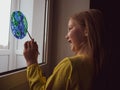 Cute little girl painting planet on window at home 4K. Happy Earth Day April 22 greeting message.Creative family leisure