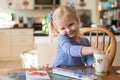 Cute little girl with paints at the kitchen table