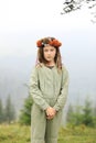 Cute little girl in a pastel jumpsuit with a colorful wreath on her head. Portrait of a girl in nature. A little girl outdoors in Royalty Free Stock Photo