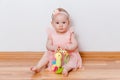Cute little girl in peach dress sits at home on the floor Royalty Free Stock Photo