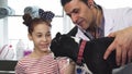 Cute little girl petting her dog during medical examination at the vet clinig