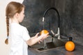 cute little girl with a pigtail intently washes oranges in the sink in the kitchen Royalty Free Stock Photo