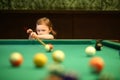 Cute little girl with pigtails playing pool in the Royalty Free Stock Photo