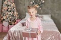 Cute little girl in pink dress with present on background Christmas tree. Merry Christmas and Happy Holidays! Baby healthy and Royalty Free Stock Photo