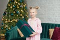 Cute little girl in pink dress with present on background Christmas tree. Merry Christmas and Happy Holidays! Baby healthy and Royalty Free Stock Photo