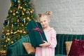 Cute little girl in pink dress with present on background Christmas tree. Merry Christmas and Happy Holidays! Baby healthy and Royalty Free Stock Photo