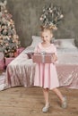 Cute little girl in pink dress with present on background Christmas tree. Merry Christmas and Happy Holidays! Baby healthy and Royalty Free Stock Photo