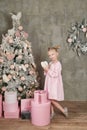 Cute little girl in pink dress with present on background Christmas tree. Merry Christmas and Happy Holidays! Baby healthy and Royalty Free Stock Photo