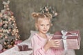 Cute little girl in pink dress with present on background Christmas tree. Merry Christmas and Happy Holidays! Baby healthy and Royalty Free Stock Photo