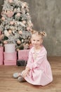 Cute little girl in pink dress with present on background Christmas tree. Merry Christmas and Happy Holidays! Baby healthy and Royalty Free Stock Photo