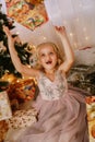 Cute little girl in pink dress with present on background Christmas tree Royalty Free Stock Photo