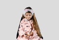A cute little girl in a pink robe and a blue ribbon in her hair looks at the powder thinking about applying it to her Royalty Free Stock Photo