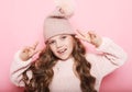 cute little girl in pink sweater and winter hat showing victory sign Royalty Free Stock Photo