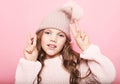 Cute little girl in pink sweater and winter hat showing victory sign Royalty Free Stock Photo