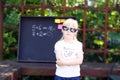 Cute little girl with pixel glasses standing ahead blackboard