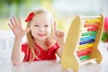 Cute little girl playing with abacus at home. Smart child learning to count. Royalty Free Stock Photo