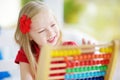 Cute little girl playing with abacus at home. Smart child learning to count. Royalty Free Stock Photo