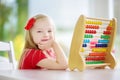 Cute little girl playing with abacus at home. Smart child learning to count. Royalty Free Stock Photo