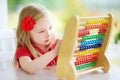 Cute little girl playing with abacus at home. Smart child learning to count. Royalty Free Stock Photo