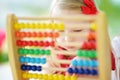 Cute little girl playing with abacus at home. Smart child learning to count. Royalty Free Stock Photo