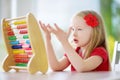 Cute little girl playing with abacus at home. Smart child learning to count. Royalty Free Stock Photo