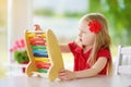 Cute little girl playing with abacus at home. Smart child learning to count. Royalty Free Stock Photo