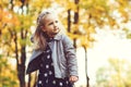 Cute little girl playing in autumn park. Happy child playing with fallen leaves. Autumn kids fashion. Happy childhood. Fashionable Royalty Free Stock Photo