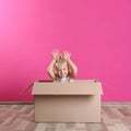 Cute little girl playing with cardboard box near wall Royalty Free Stock Photo